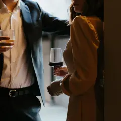 En man i kostym håller ett glas whisky, en kvinna i klänning håller ett glas rödvin. Kanske är det dags för några frågor till killar?