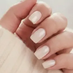 En hand med ljusa, mandelformade naglar i en mjuk, krämig färg. Perfekt almond nails inspo för en elegant look.