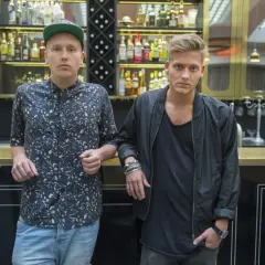 Sonny Fahlberg och en vän står vid en bardisk med flaskor i bakgrunden.