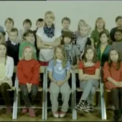 Veronica Maggio barn i en klassrumsmiljö. En grupp barn sitter på stolar framför en lärare.