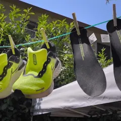 Två par neongröna löparskor och två svarta innersulor hänger på tork. Nike Move to Zero-filosofin syns i detaljerna.