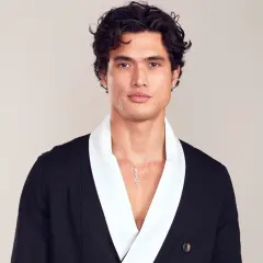 Charles Melton bär en svart kavaj med vit krage och ett diamant-halsband.