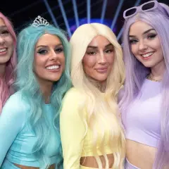 Fyra glada tjejer med färgglatt hår, som en tube girl-grupp, poserar för en bild.