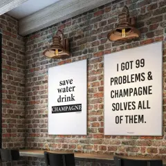 Två tavlor med preppy text på en tegelvägg. En säger "save water drink CHAMPAGNE", den andra "I GOT 99 PROBLEMS & CHAMPAGNE SOLVES ALL OF THEM.
