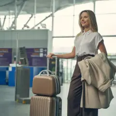 Snygg flyg outfit med en kvinna som står med resväskor på en flygplats.