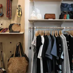 Hängande kläder och accessoarer i en butik. En hel del kläder, väskor och smycken som kan utgöra en komplett outfit.