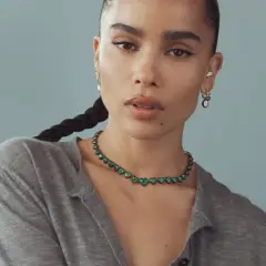 Zoe Kravitz stil: en kvinna med flätat hår bär en grön hjärtformad halsband och örhängen.