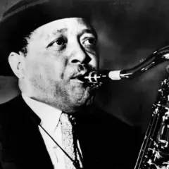 En man med hatt spelar saxofon. Hans musik är så cool, en riktig synonym för jazzens själ.