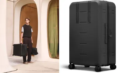 En man med snygga resväskor i modern arkitektur. En svart, robust resväska med hjul visas i detalj.