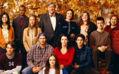 Hela rollistan i Gilmore Girls samlad framför höstfärgat lövverk. En ikonisk ensemblebild som fångar seriens charm.