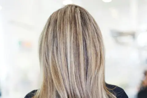 En frisyr med brunt hår med kalla slingor som ger en naturlig och modern look.