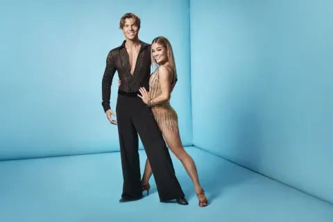 Lets dance deltagare redo för dansgolvet. Han i svart skjorta med stenar, hon i glittrig gul klänning.