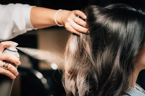 Hårstylist fixar en elegant edgar hairstyle med hårspray.