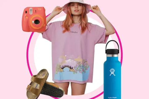 En vsco girl med rosa t-shirt, bucket hat, Instax-kamera, Birkenstocks och en blå Hydro Flask.