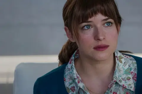 Dakota Johnson with blue eyes and brown hair, wearing a floral shirt and teal cardigan.