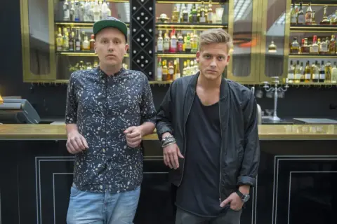 Sonny Fahlberg och en vän står vid en bardisk med flaskor i bakgrunden.