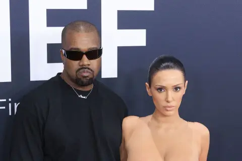 Kanye West och Bianca Censori poserar framför en stor logotyp.