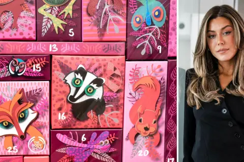 En kvinna står bredvid en Caia kalender med djurmotiv. Kalendern är rosa och har illustrationer av en räv, en grävling och en ekorre.