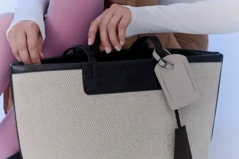 En person med rosa strumpbyxor och vit tröja stoppar ner handen i en necessär från Day Birger et Mikkelsen.