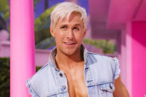 Ryan Gosling som Ken i Barbie-filmen, med blont hår och jeansväst, i en rosa värld.