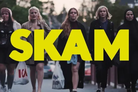 Fem tjejer går på gatan, med den stora gula texten "SKAM" över bilden. En av dem dricker ur en flaska.