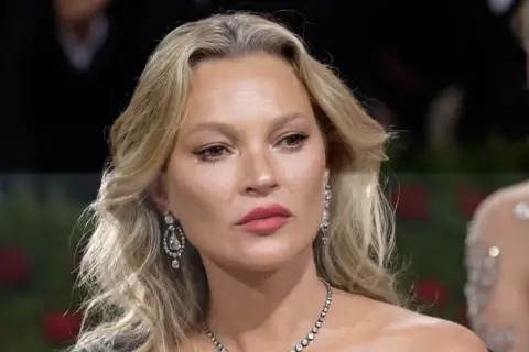 Kate Moss-stil med blont hår, diamantörhängen och en elegant halsband.