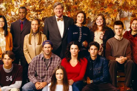 Hela rollistan i Gilmore Girls samlad framför höstfärgat lövverk. En ikonisk ensemblebild som fångar seriens charm.