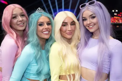 Fyra glada tjejer med färgglatt hår, som en tube girl-grupp, poserar för en bild.