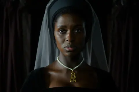 En kvinna i historisk dräkt, med slöja och pärlhalsband, i en scen från anne boleyn series.