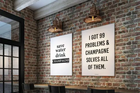 Två tavlor med preppy text på en tegelvägg. En säger "save water drink CHAMPAGNE", den andra "I GOT 99 PROBLEMS & CHAMPAGNE SOLVES ALL OF THEM.