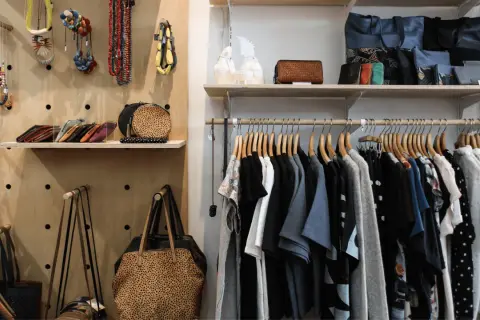 Hängande kläder och accessoarer i en butik. En hel del kläder, väskor och smycken som kan utgöra en komplett outfit.