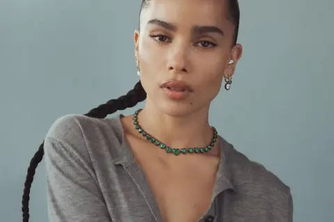Zoe Kravitz stil: en kvinna med flätat hår bär en grön hjärtformad halsband och örhängen.