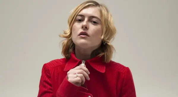 Ellen Krauss i röd manchesterjacka, med fingret vid dragkedjan.