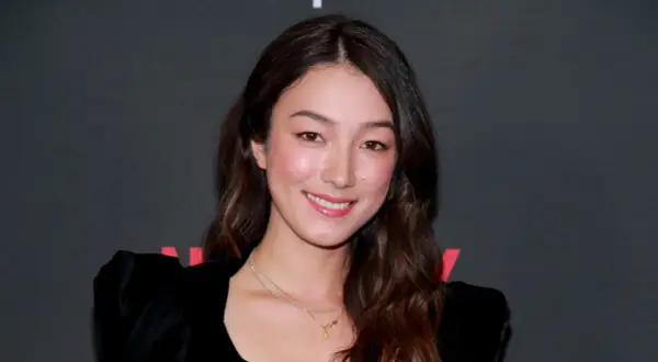 Natasha Liu Bordizzo ler glatt i en svart klänning med puffärmar.