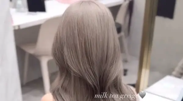 En person med vackert, långt hår i en mjuk nyans av mjölktegreige. De subtila blonda slingorna i det grå håret ger en sofistikerad och modern look.