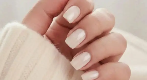 En hand med ljusa, mandelformade naglar i en mjuk, krämig färg. Perfekt almond nails inspo för en elegant look.