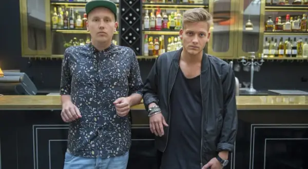 Sonny Fahlberg och en vän står vid en bardisk med flaskor i bakgrunden.