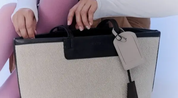 En person med rosa strumpbyxor och vit tröja stoppar ner handen i en necessär från Day Birger et Mikkelsen.