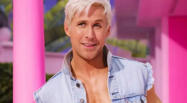 Ryan Gosling som Ken i Barbie-filmen, med blont hår och jeansväst, i en rosa värld.