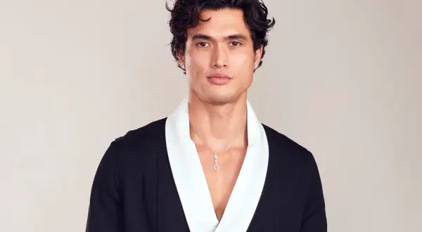 Charles Melton bär en svart kavaj med vit krage och ett diamant-halsband.