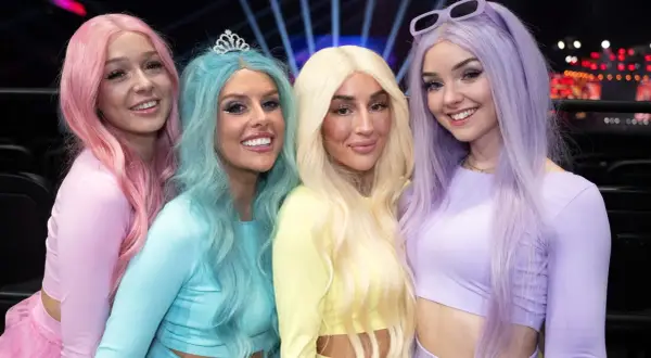 Fyra glada tjejer med färgglatt hår, som en tube girl-grupp, poserar för en bild.
