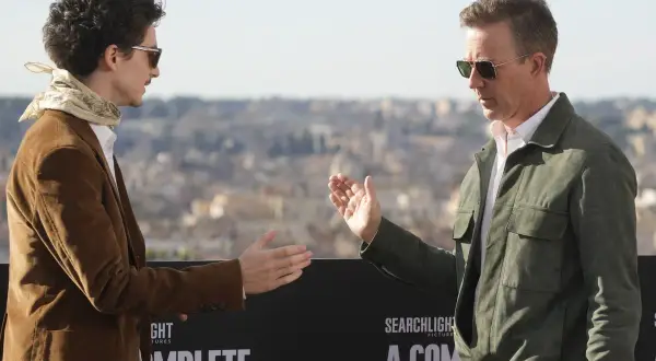 Timothée Chalamet och Edward Norton gestikulerar framför en bakgrund med texten "A Complete Unknown", en av filmerna med Timothée Chalamet.