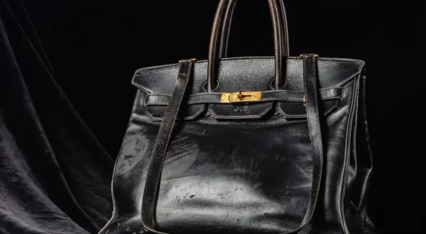 En svart, sliten läderväska i jane birkin style, med guldfärgade detaljer och initialerna J.B. präglade.