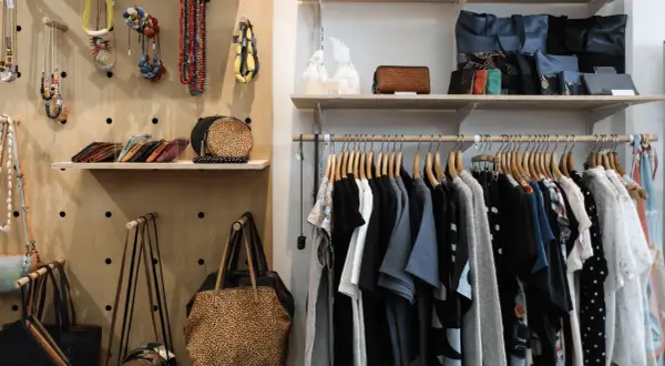 Hängande kläder och accessoarer i en butik. En hel del kläder, väskor och smycken som kan utgöra en komplett outfit.
