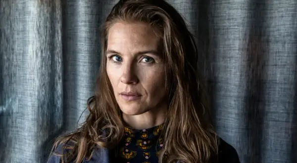 Lisa Carlehed, med blå ögon och brunt hår, blickar intensivt mot kameran. Hon bär en mörkblå jacka över en mönstrad tröja.