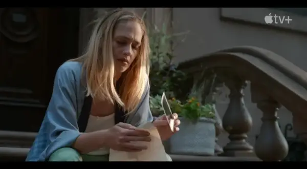 Jemima Kirke sitter på trappan och läser ett brev med en kniv i handen. En scen från filmer och tv-program med Jemima Kirke.