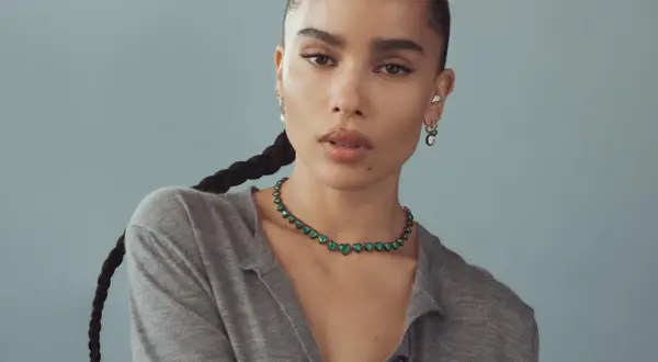 Zoe Kravitz stil: en kvinna med flätat hår bär en grön hjärtformad halsband och örhängen.