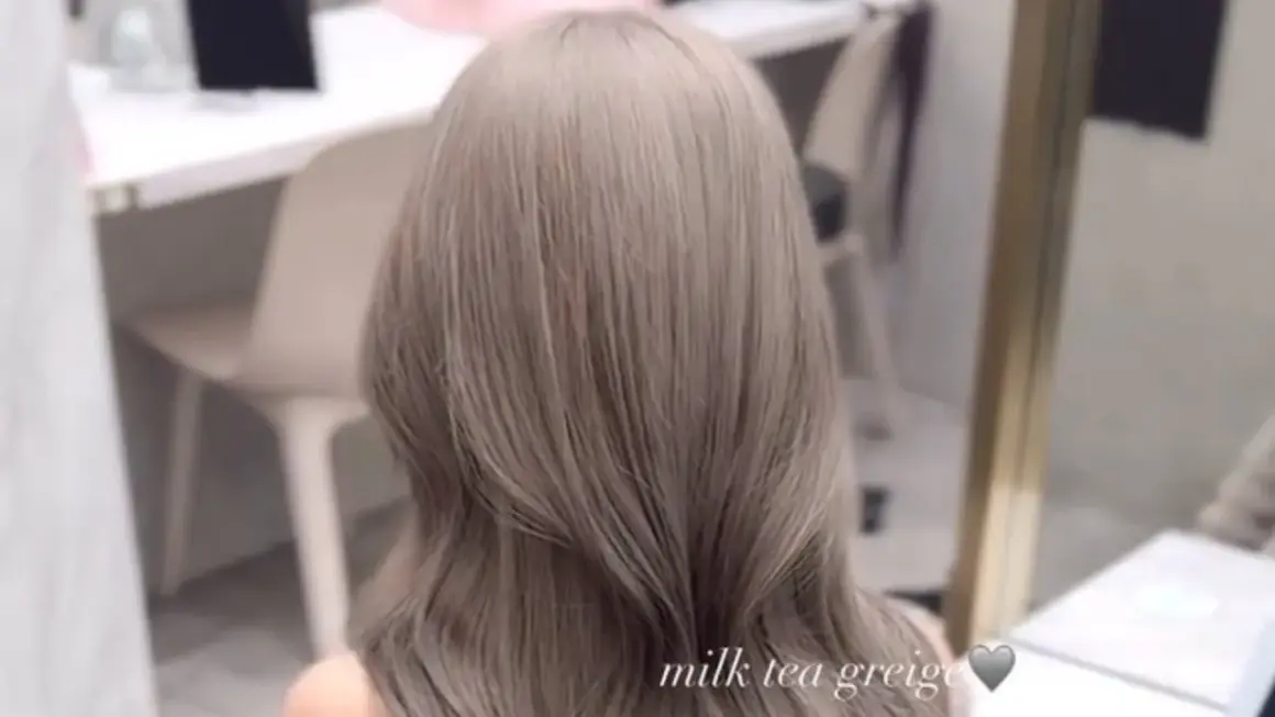 En person med vackert, långt hår i en mjuk nyans av mjölktegreige. De subtila blonda slingorna i det grå håret ger en sofistikerad och modern look.