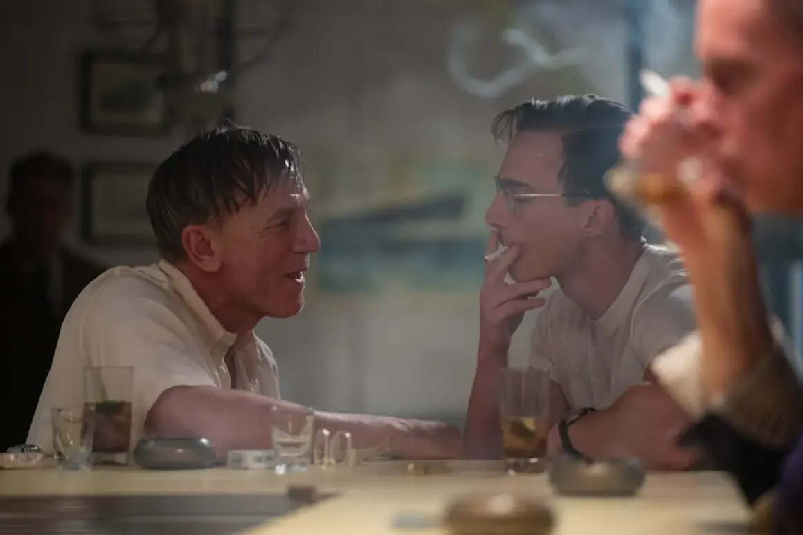 Två män samtalar vid ett bord, en röker cigarett. En scen från filmer med Luca Guadagnino.