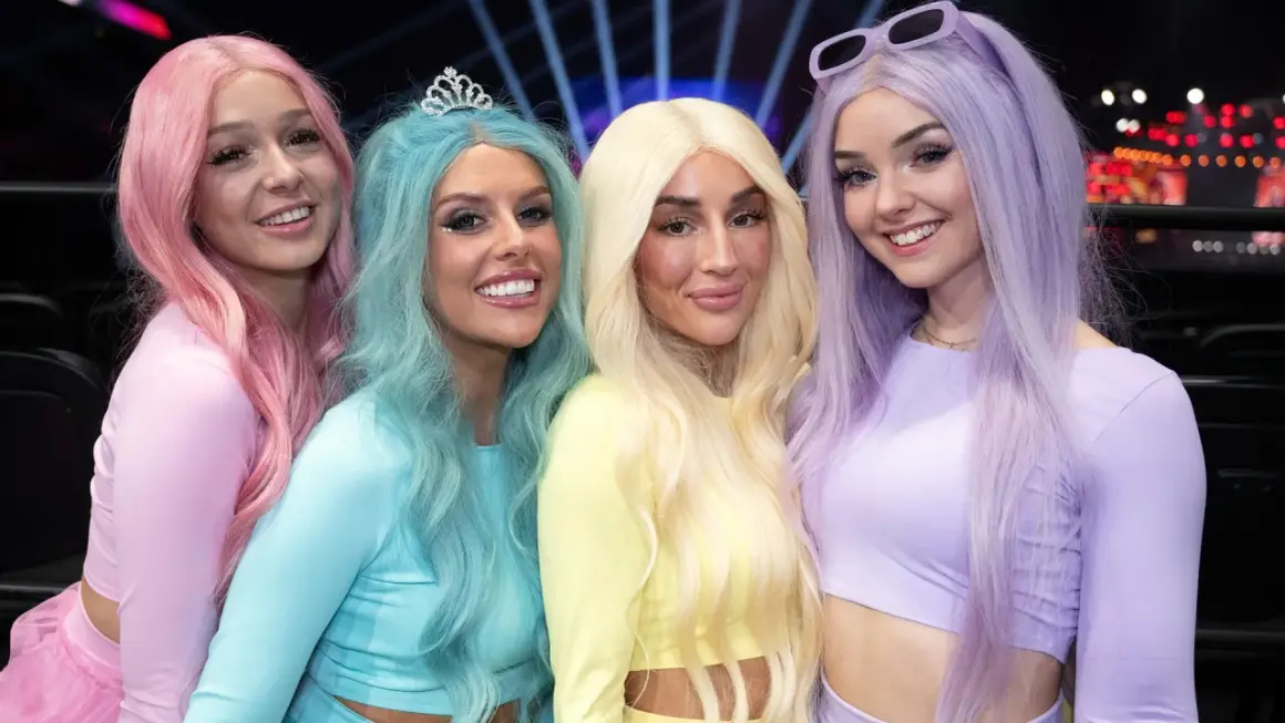 Fyra glada tjejer med färgglatt hår, som en tube girl-grupp, poserar för en bild.